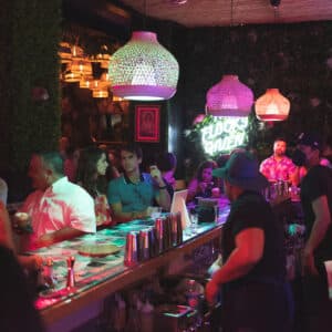 This is an image of Tipsy Flamingo in Downtown Miami. It shows a bartender behind the bar preparing a cocktail for a guest.